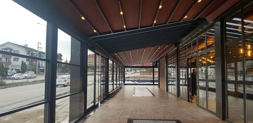 Rolling Roof: Cadde kenarında uzun kapalı teras, ışıklı örtü