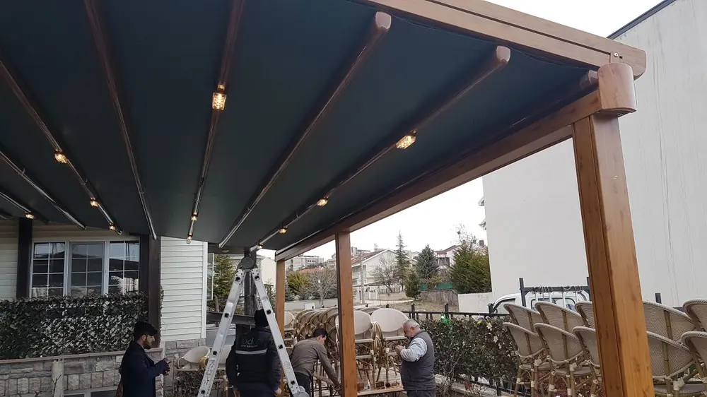 Tente Pergola: Ahşap görünümlü dikmelerde koyu kumaşlı tente pergola