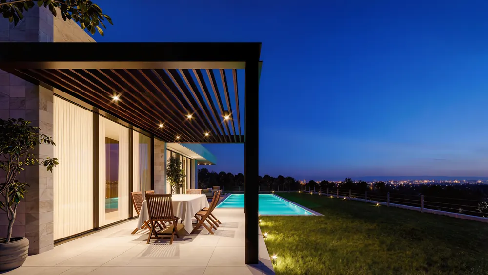 Akşam, havuz kenarında eve bitişik antrasit bioklimatik pergola